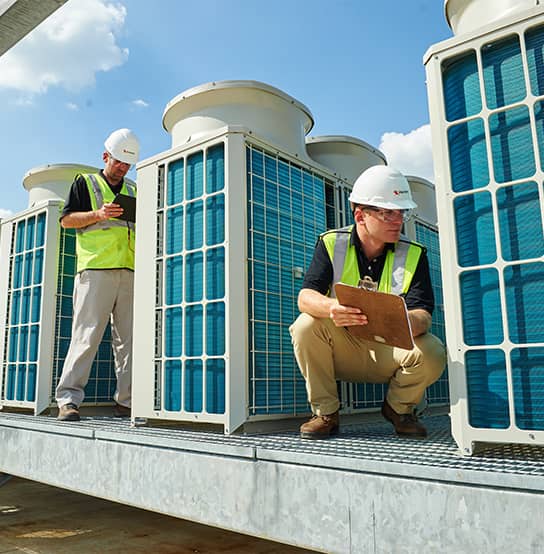 two facility workers wearing hardhats and vests